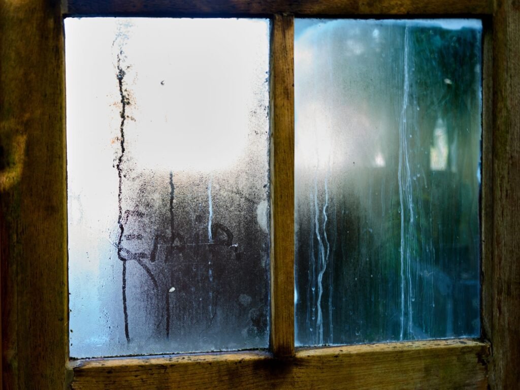 Heavy condensation running down the panes of an old wooden window frame