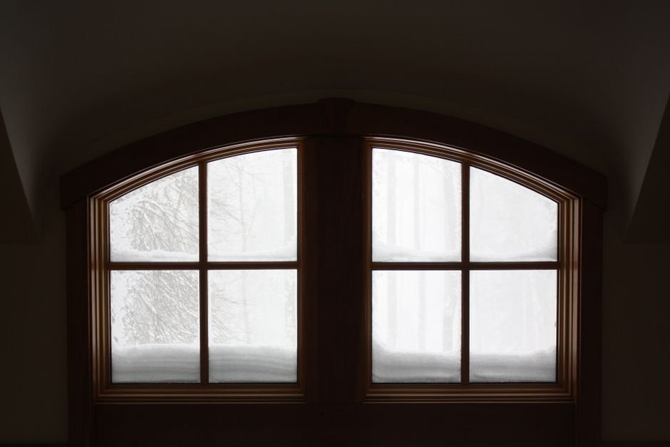 Deep snow outside a window seen from indoors, the conditions in which a dehumidifier in winter often runs fan-only rather than collecting water