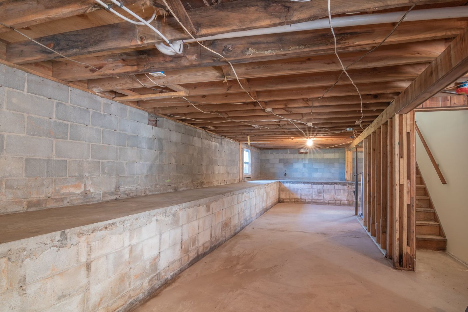Unfinished basement with concrete block walls and exposed floor joists, a common place for a dehumidifier