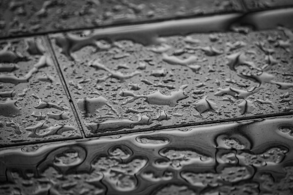 Water pooled and beaded on a tiled floor, the first sign of a dehumidifier leaking