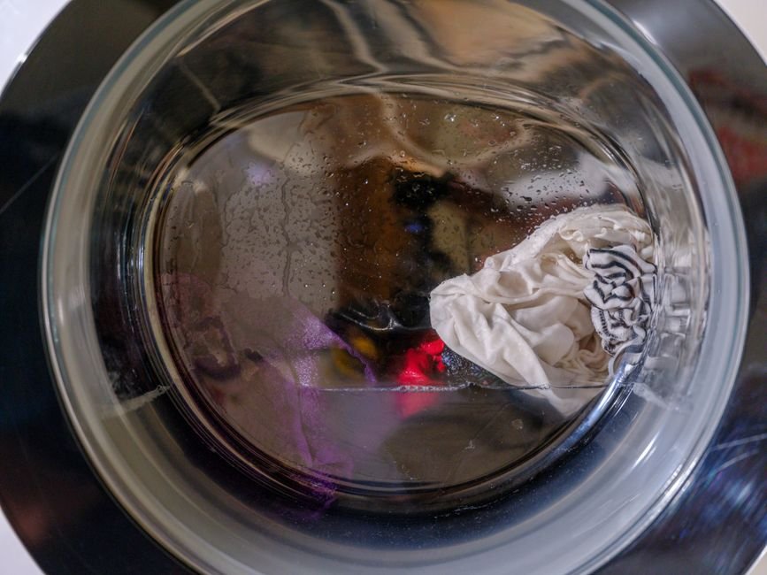 Wet washing in a front-loading machine drum, the load that releases roughly two litres of water into a room when dried indoors