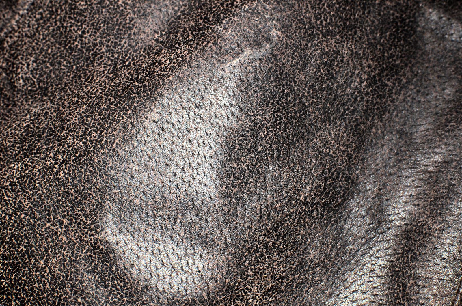 Close-up of dark aged leather with a cracked, worn surface