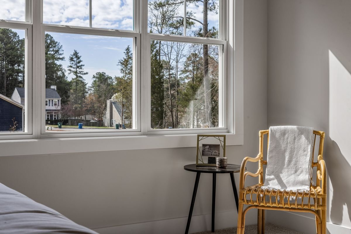 Bedroom corner with a large multi-pane window, an outside wall and a small chair and side table