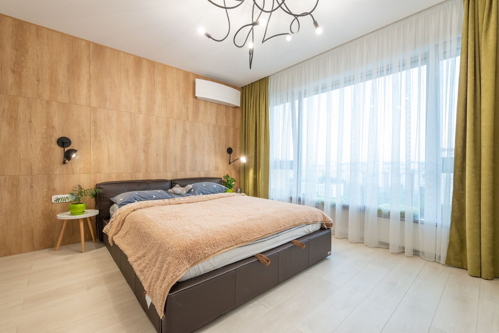Bedroom with floor-to-ceiling windows, sheer curtains and heavy green curtains pulled to the side