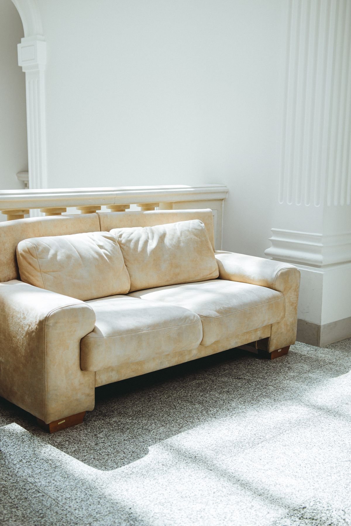 Beige two-seat sofa with soft cushions in a bright sunlit room