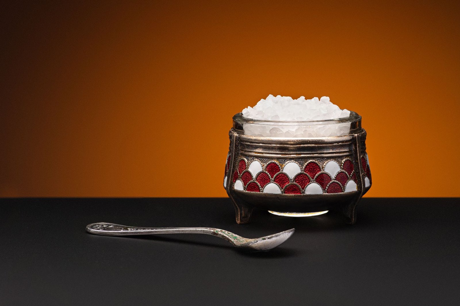 Metal bowl of coarse white rock salt with a spoon, the cheapest homemade moisture absorber