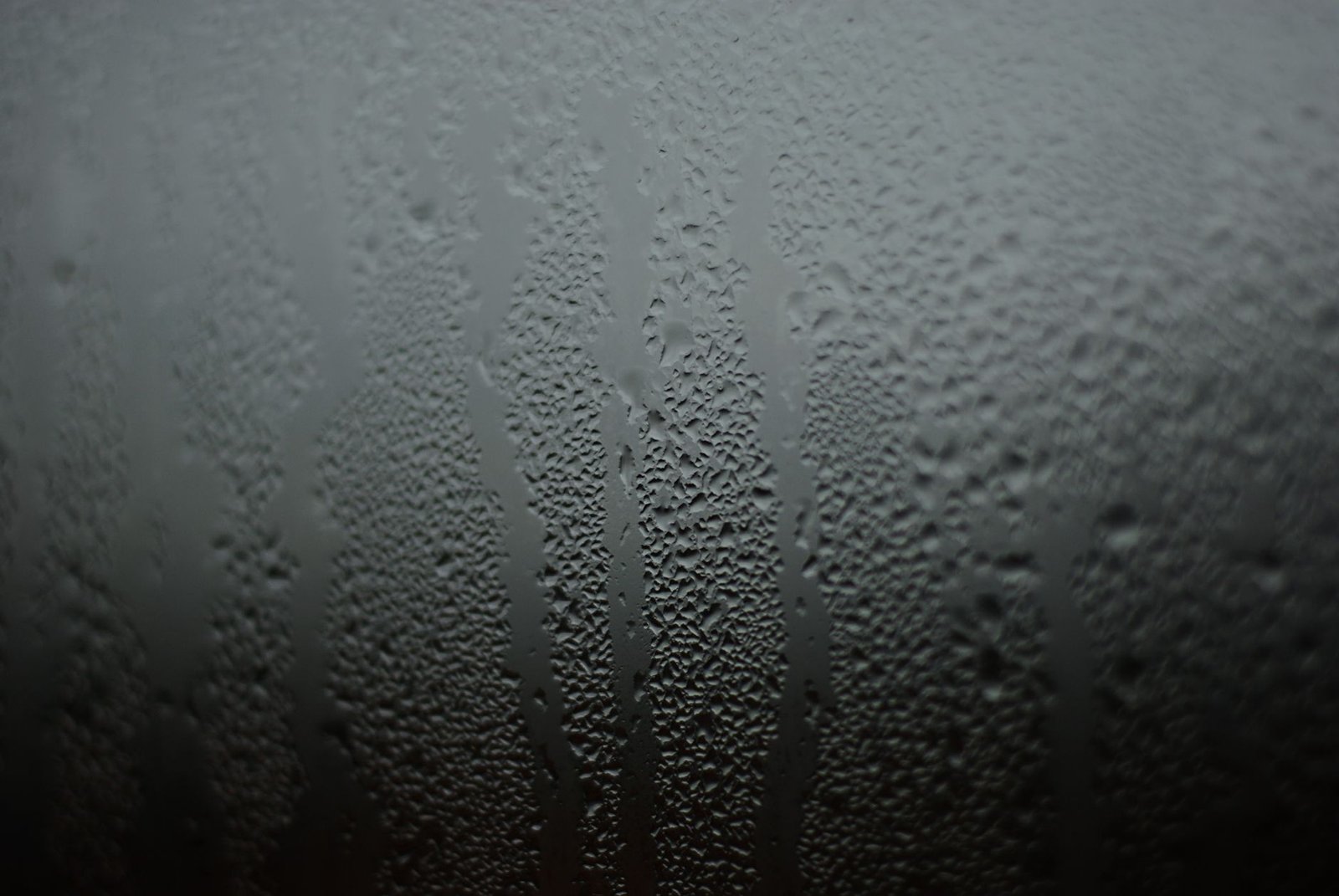 Fine water droplets and running streaks of condensation on a cold window pane