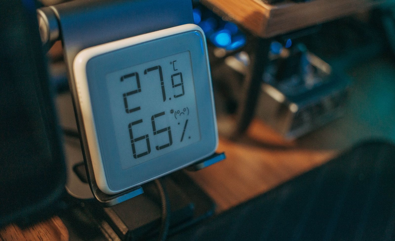 Digital hygrometer on a stand showing 27.9 degrees Celsius and 65 percent relative humidity indoors