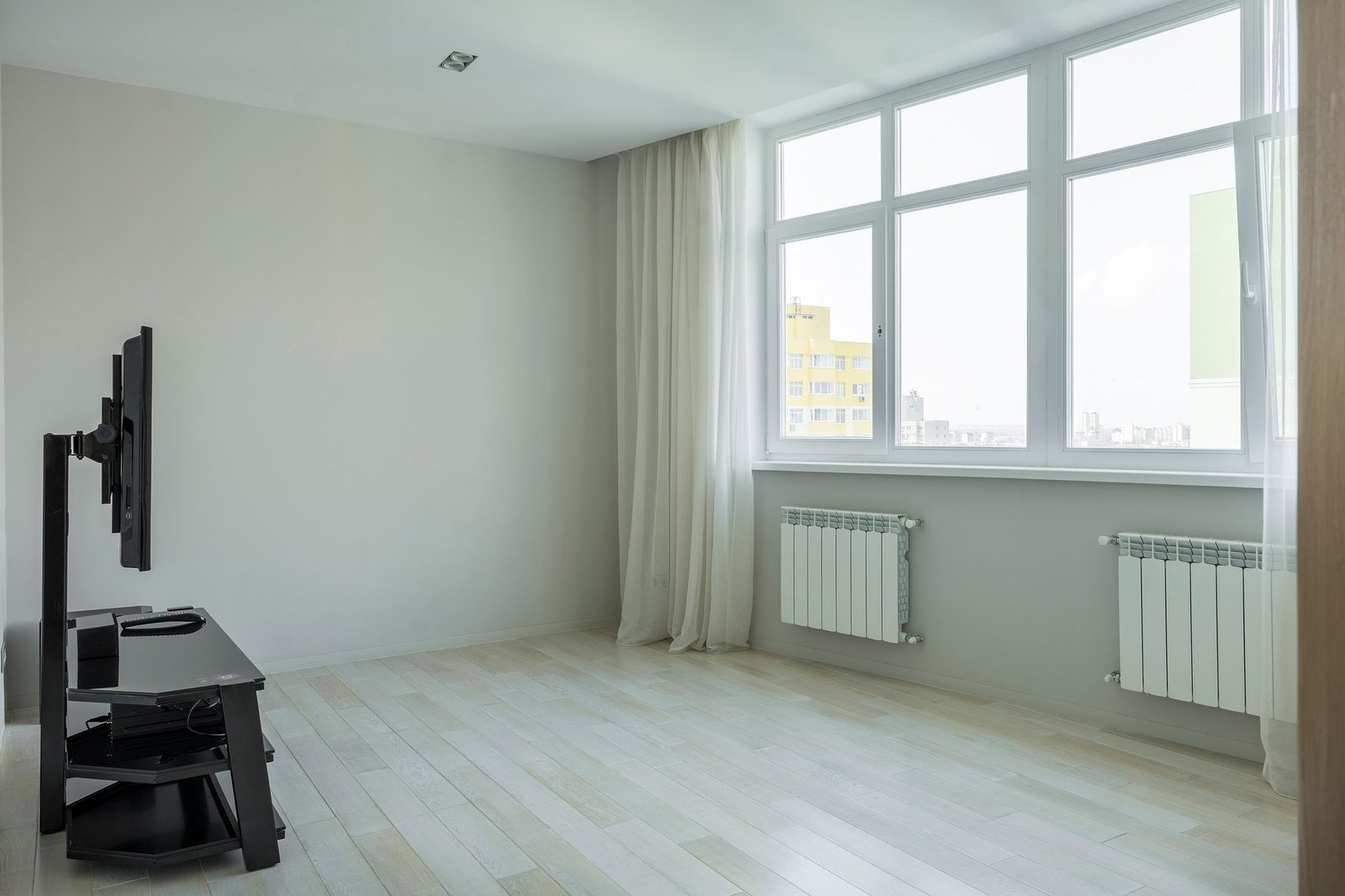 Empty bright room with radiators under a large window, the kind of space whose temperature and moisture load decide how low a dehumidifier can get