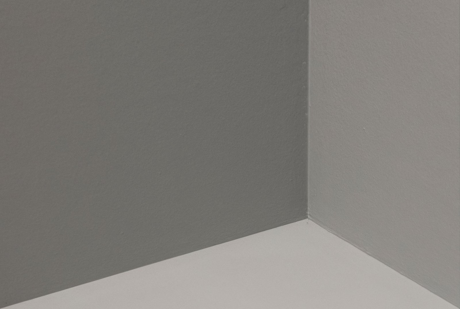 Inside corner of an empty room where two grey walls and the floor meet
