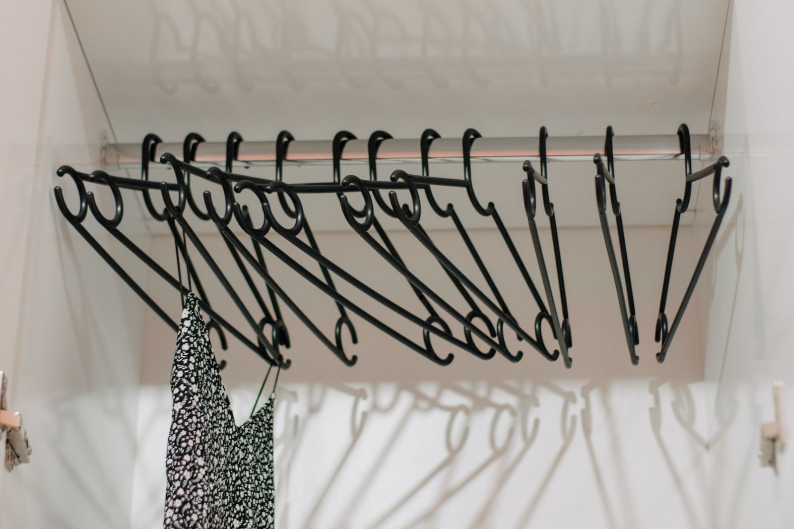 Inside a white wardrobe with black hangers on a rail, a closed space where a calcium chloride tub is used