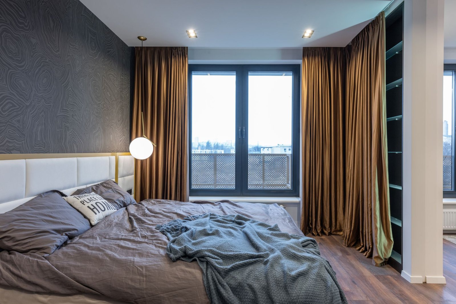 Heavy lined curtains drawn back either side of a double-glazed bedroom window, leaving the glass open to the room air