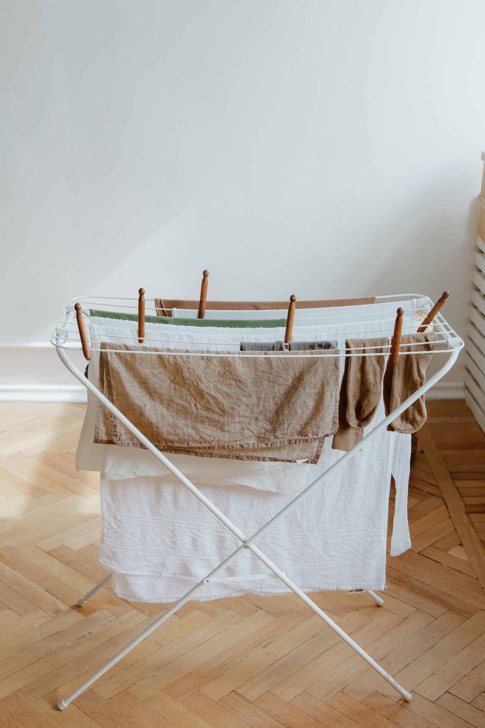 A clothes airer with a thick white towel and a linen towel hung over the bars with gaps between them