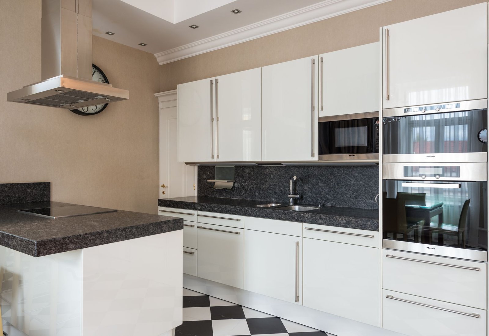 Modern kitchen with a stainless steel chimney cooker hood above an island hob