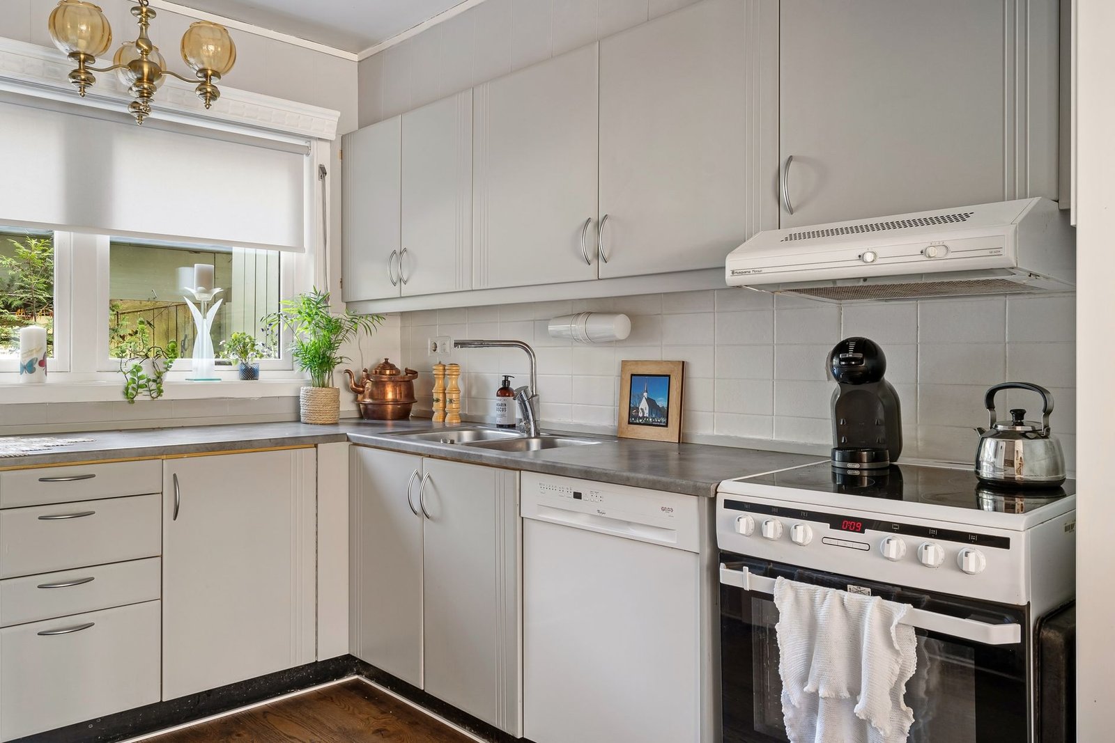 Compact white cooker hood above an electric cooker in a kitchen with a window