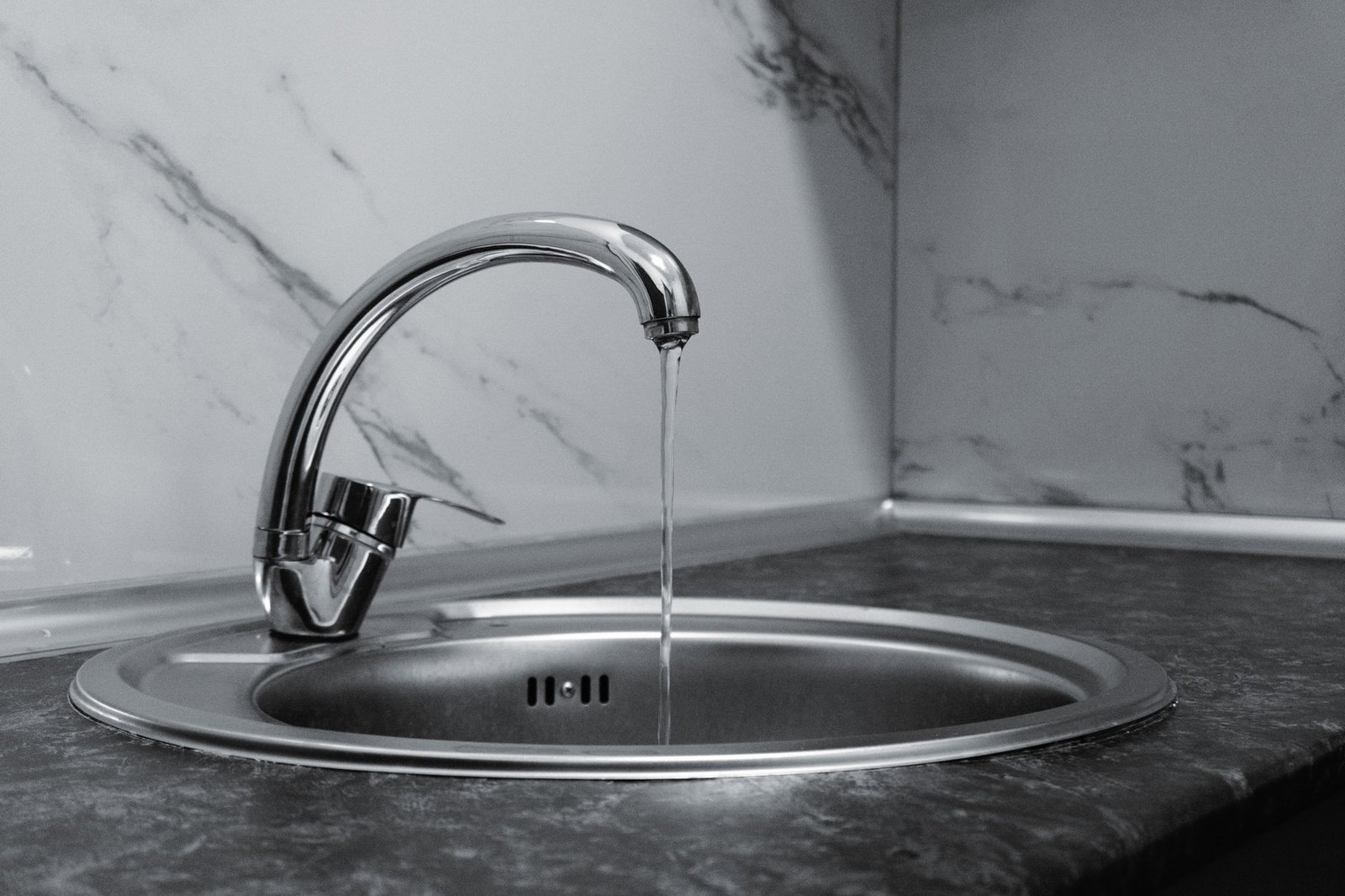 Chrome kitchen tap running into a stainless steel sink, the safe source of drinking water compared with dehumidifier tank water