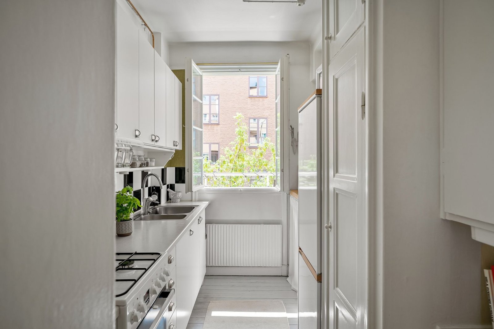 Narrow galley kitchen with a casement window open wide to let moist air out