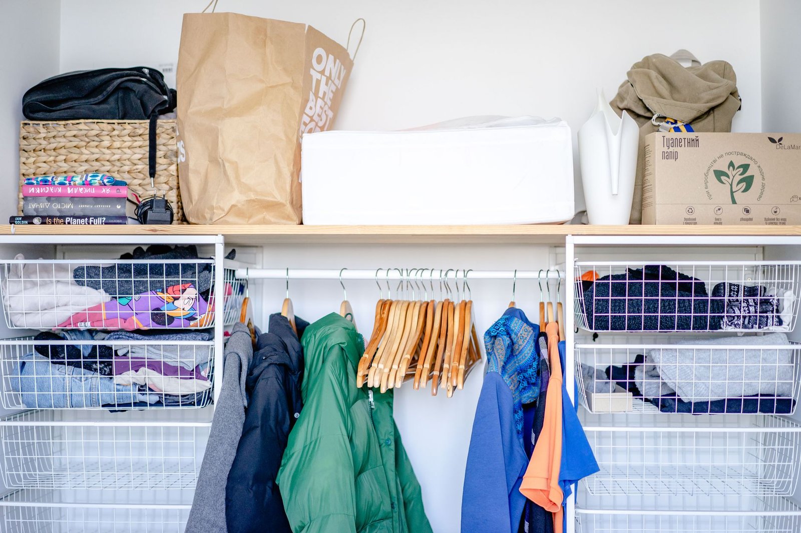 Open wardrobe with a hanging rail and wire basket shelves, clothes spaced so air can move between them