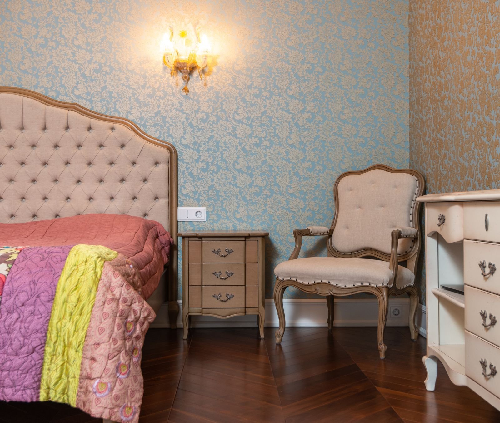 Bedroom with patterned wallpaper on dry painted walls above a wooden floor