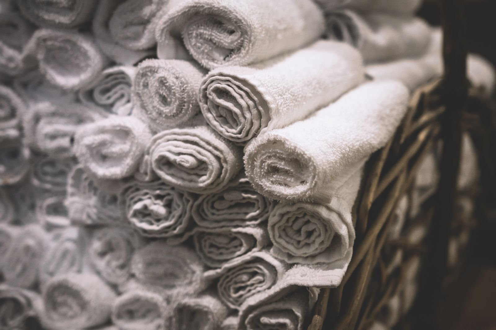 Rolled white towels stacked in a wicker basket