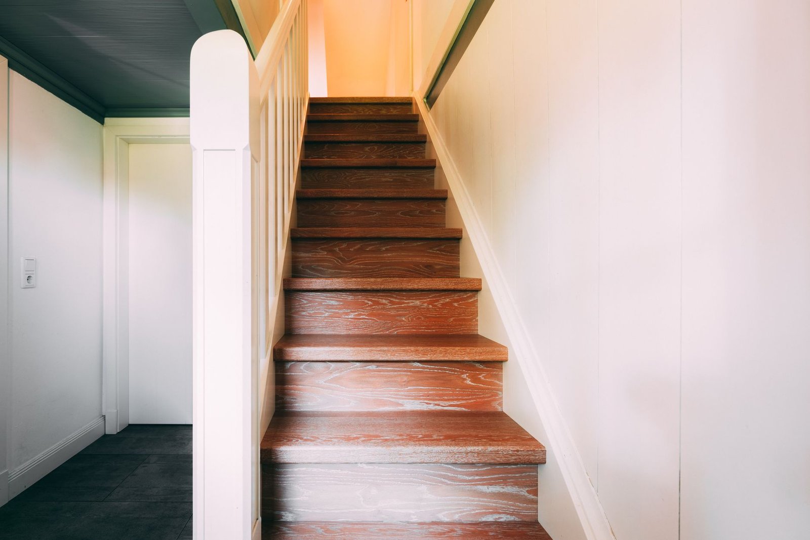 Wooden staircase leading from a ground-floor hallway to the upper floor, the kind of floor-to-floor boundary that separates dehumidifier zones
