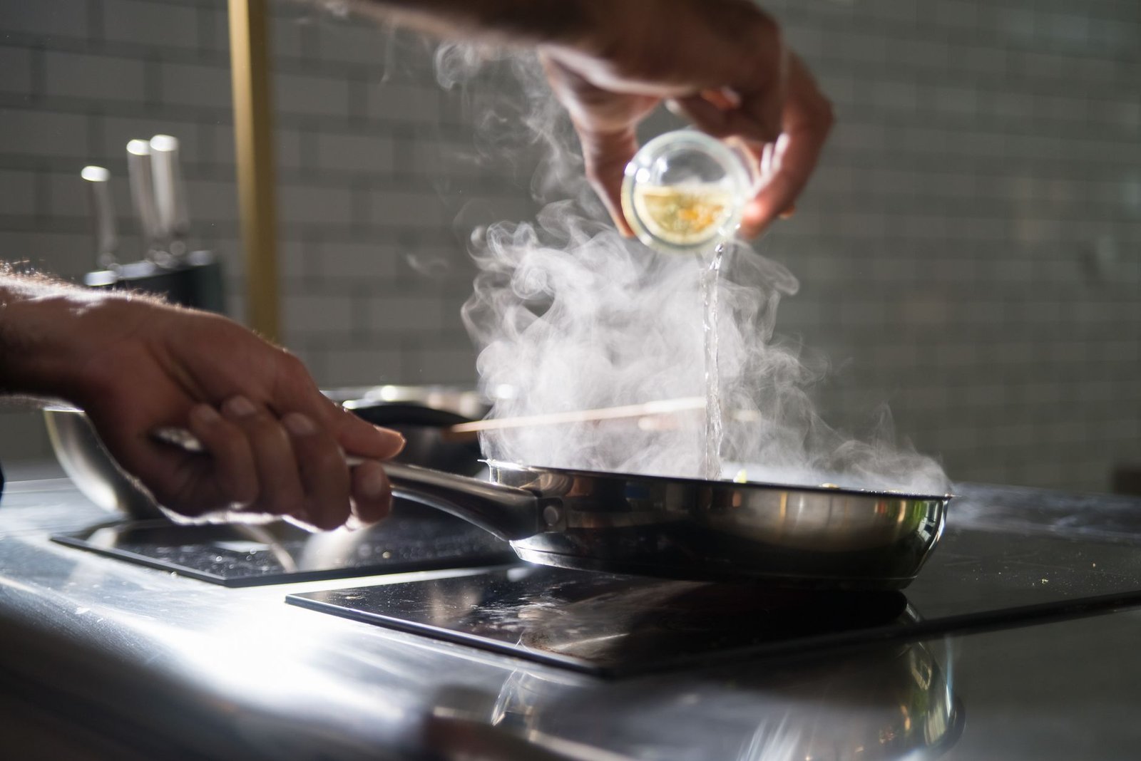 Steam rising from a frying pan on a hob as oil is poured in, the source of cooking smells