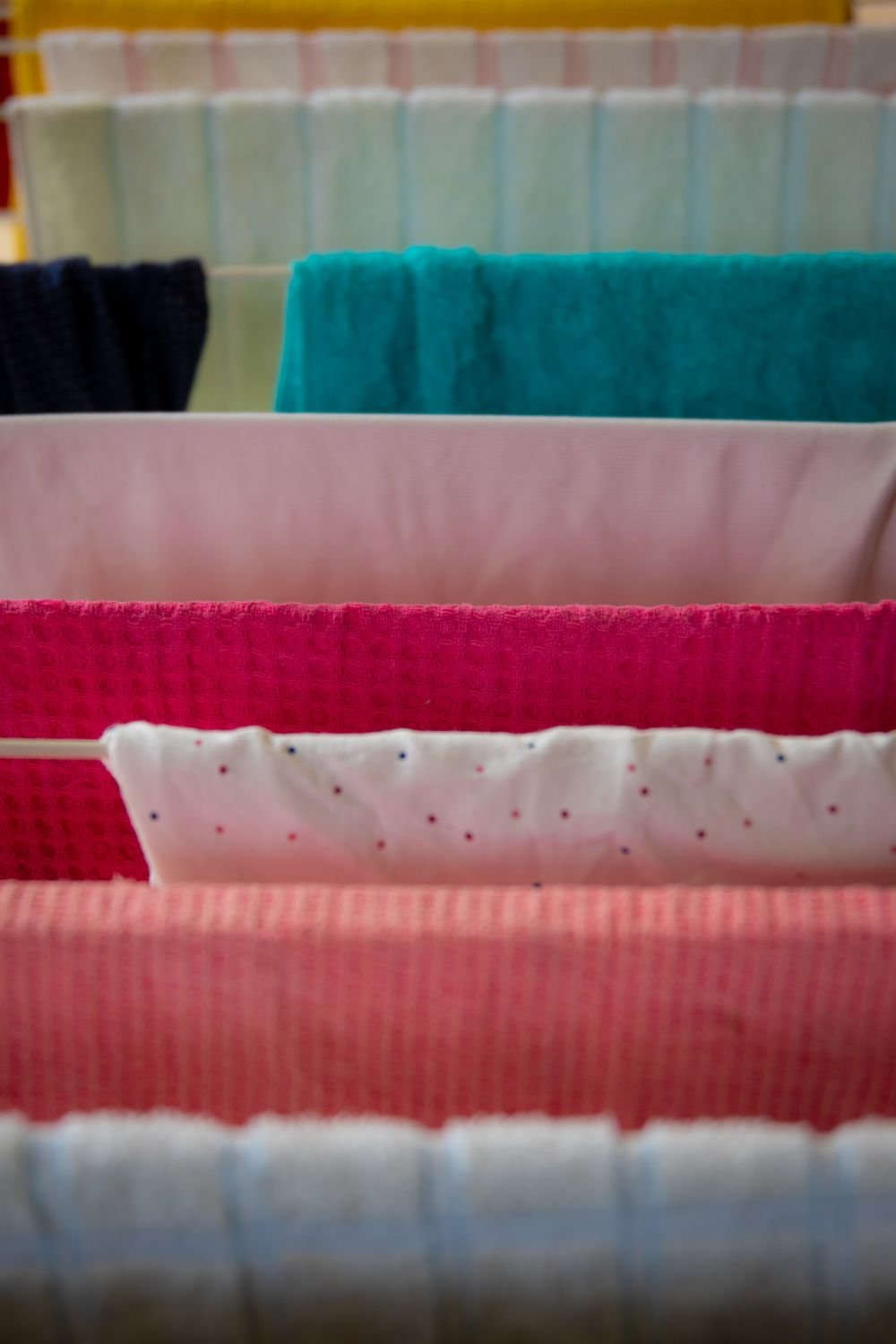 Towels and clothes hung closely on the rails of a clothes airer