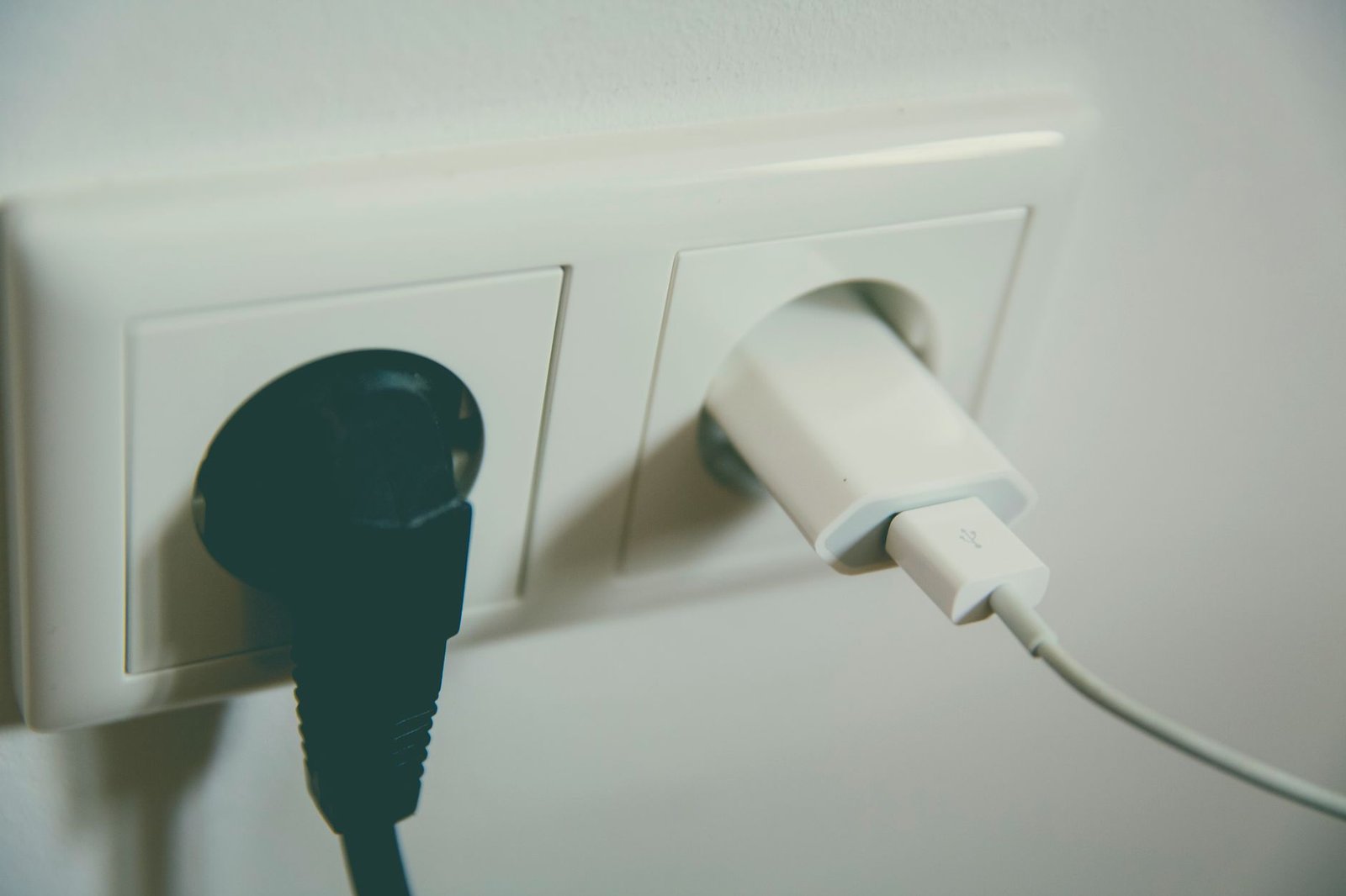 Double wall socket with a black appliance plug and a white USB charger plugged straight into it