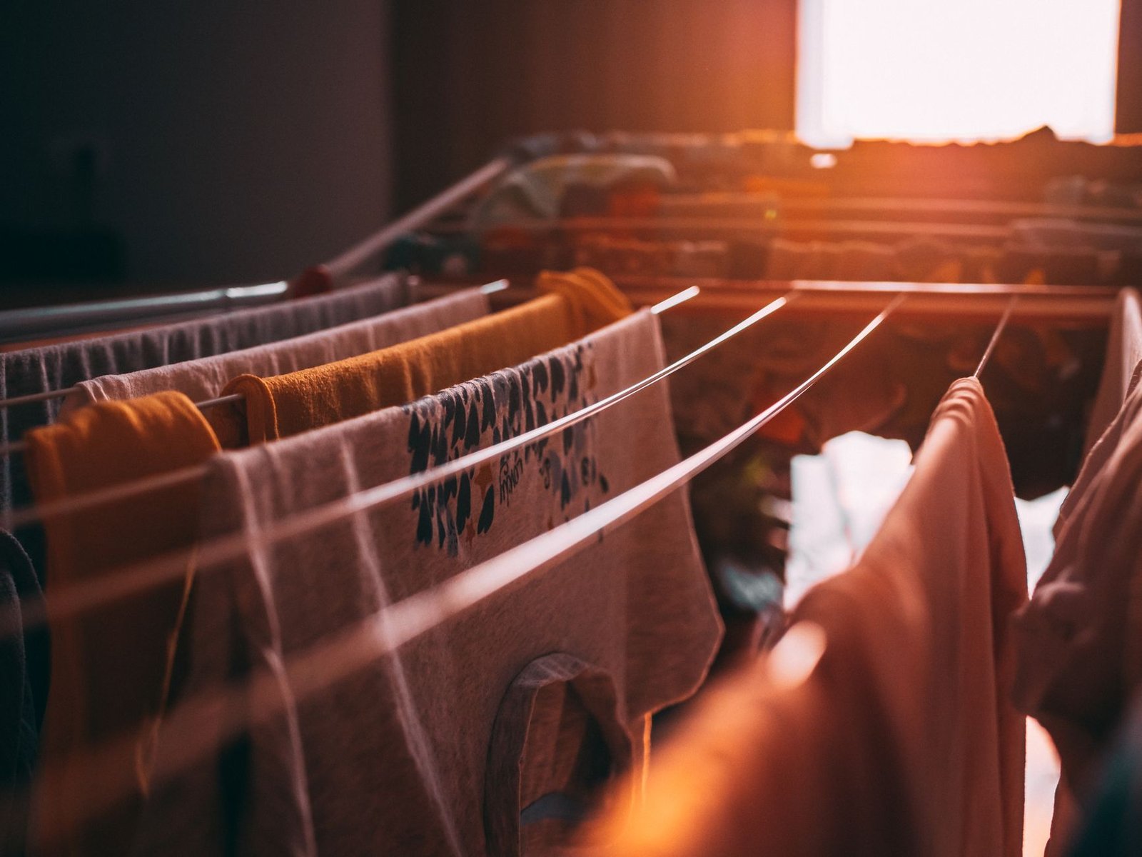 Washing hung on an indoor drying rack in warm window light, a typical load for laundry mode