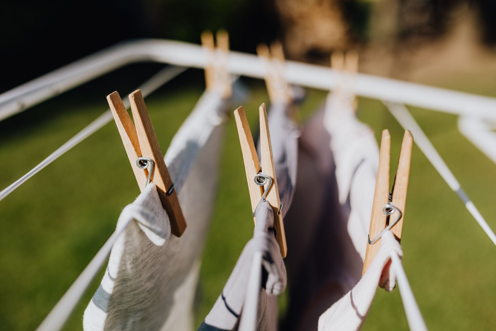 Wooden pegs holding washing on a clothes airer outdoors on a sunny day