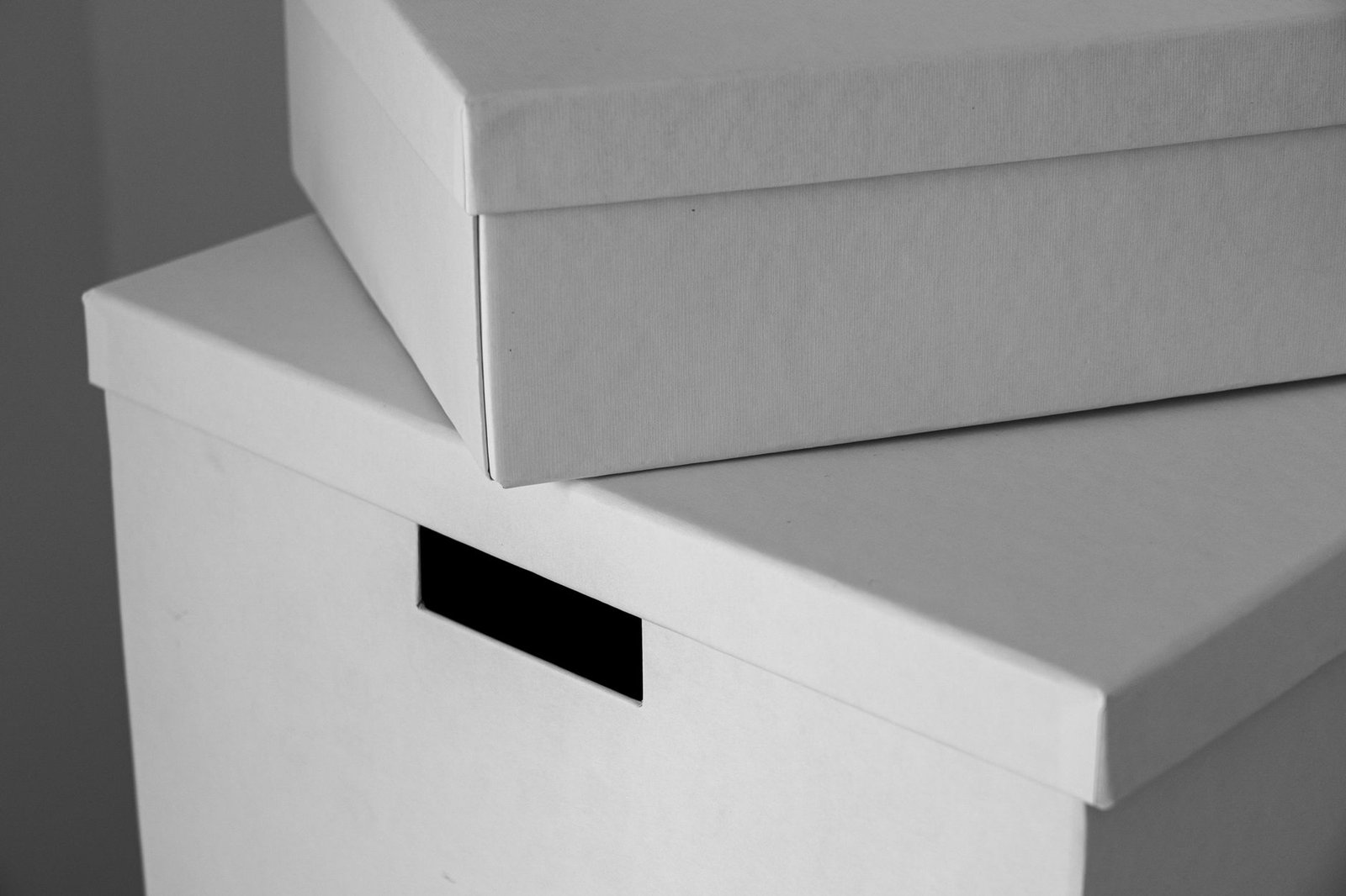 Two white cardboard storage boxes with lids stacked on top of each other