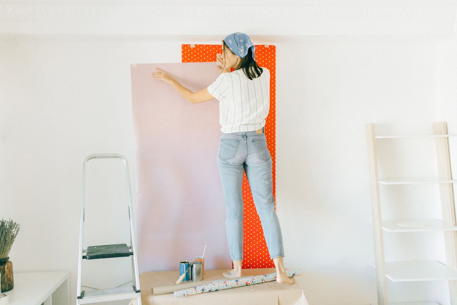 Woman smoothing a sheet of wallpaper onto a white wall