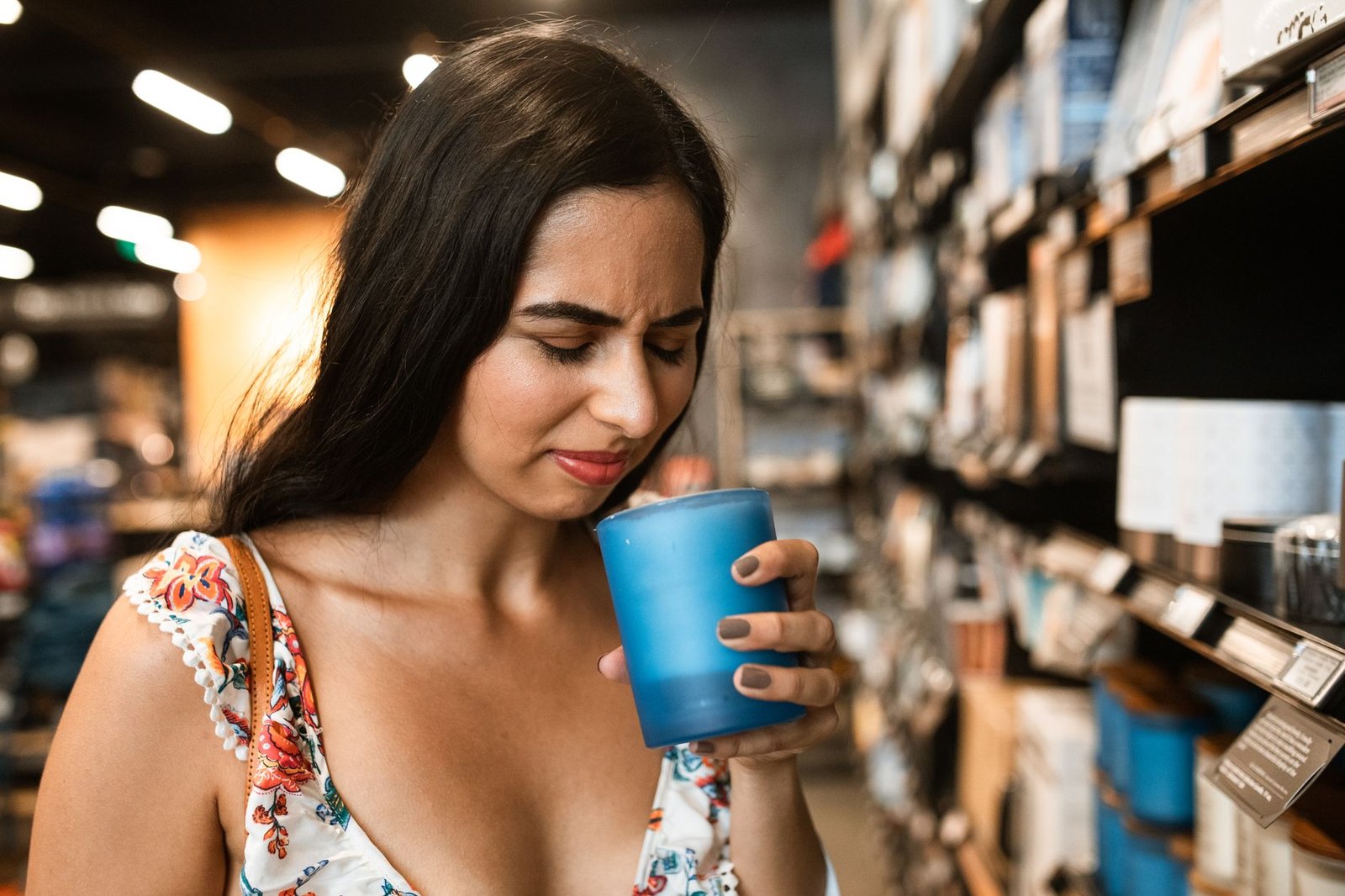 Woman wrinkling her nose as she sniffs a candle, a reaction to an unpleasant smell